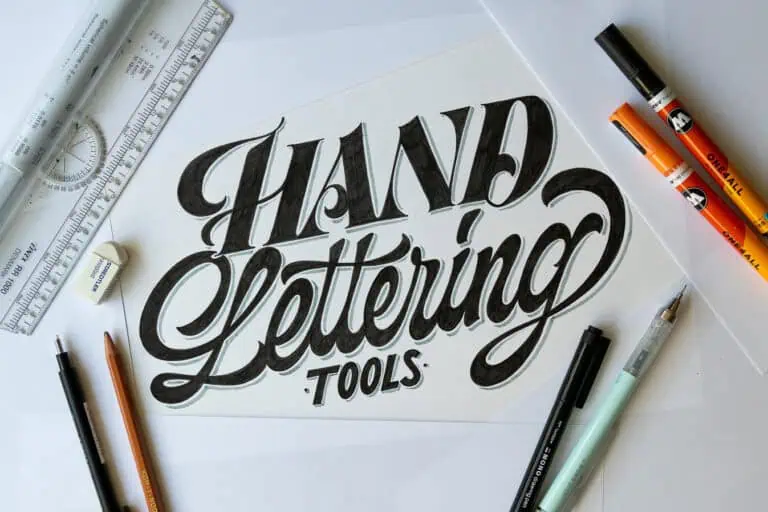 Hand lettering tools and materials on a workspace.