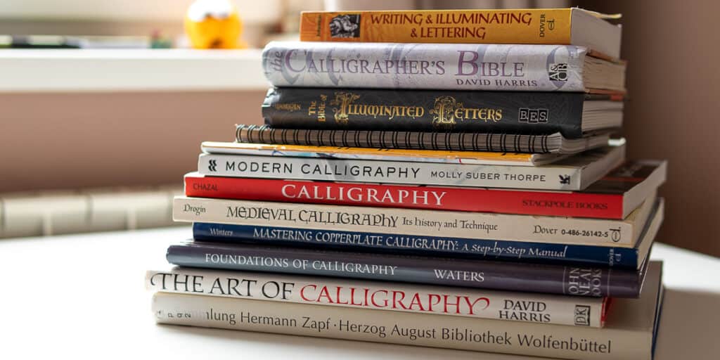 several calligraphy books stacked on top of each other. 