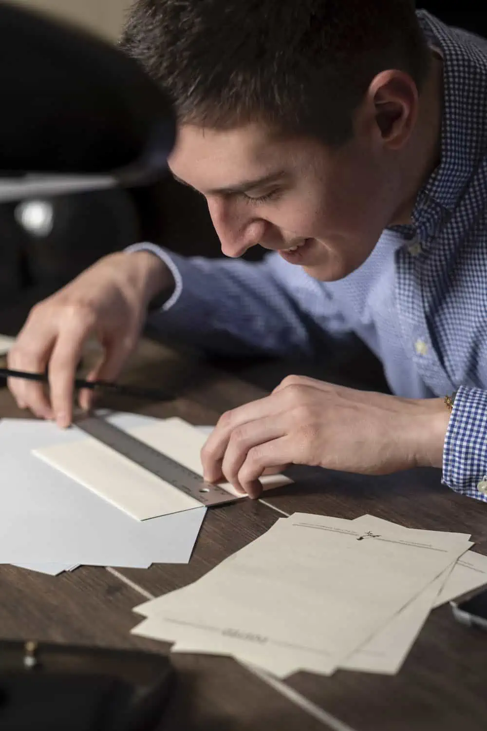 Person measuring paper with ruler and pencil.