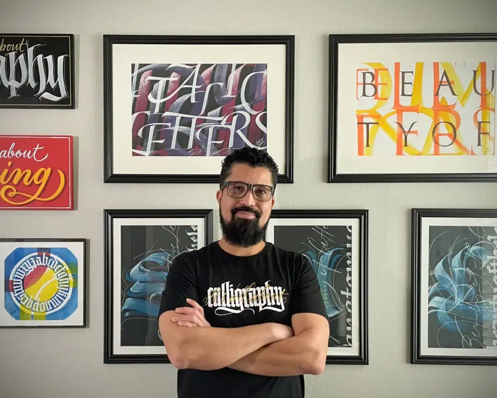 Person posing in front of calligraphy artwork.