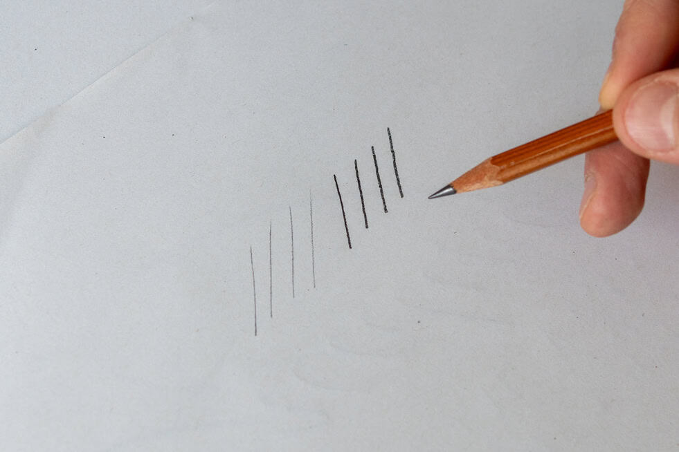 Hand drawing vertical lines with a pencil.