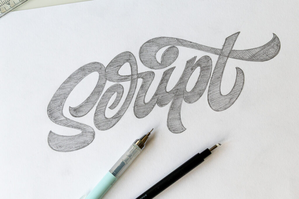 Hand-drawn script lettering on paper with pens.