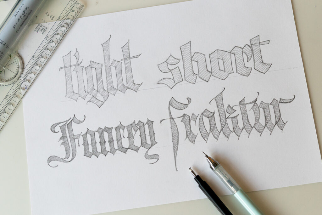 Sketch of decorative lettering examples on paper.