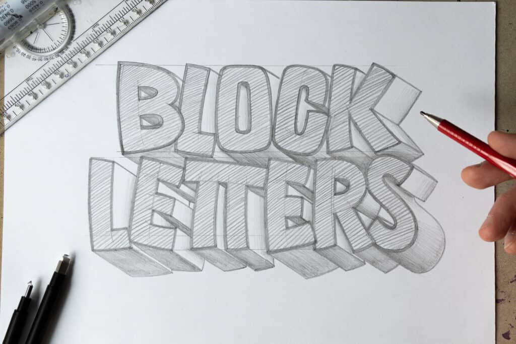 Hand drawing block letters with pencils.